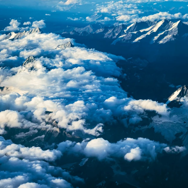 white clouds cover the mountains above a blue sky