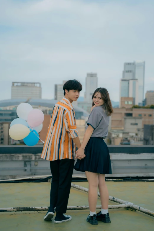 a young couple holds hands as they stand on top of a roof