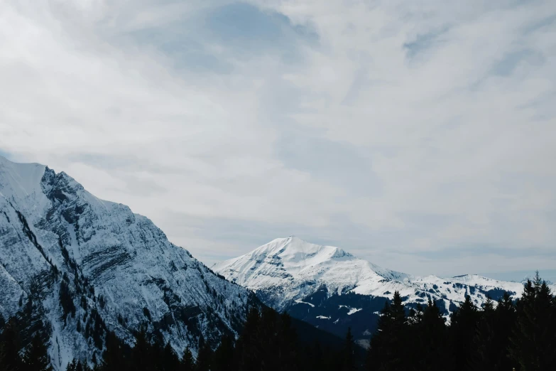 a mountain side covered in snow on a cloudy day