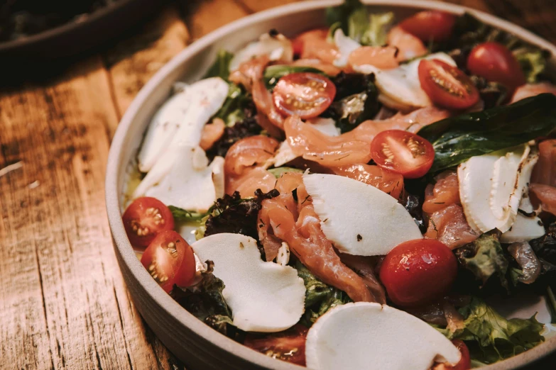 a salad with tomatoes, spinach, cheese and bacon