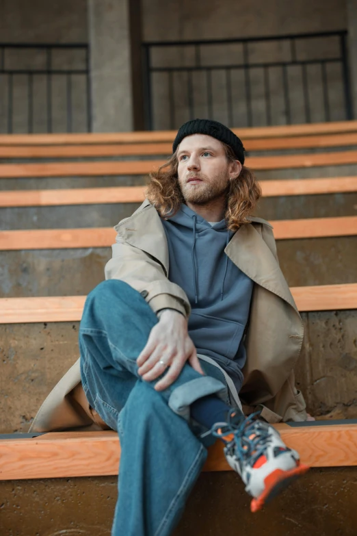 the man is sitting down on some bleachers