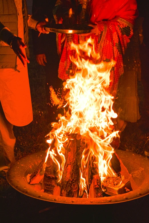 some people standing around an open fire pit