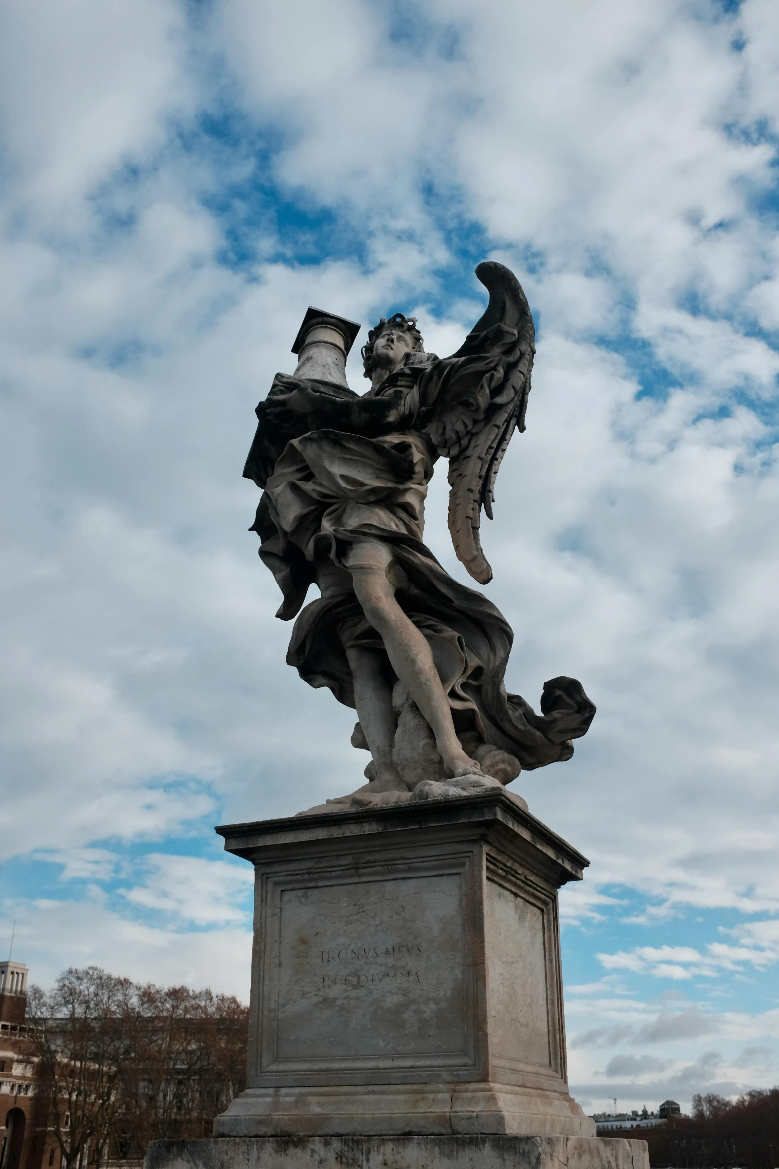 a statue sitting under a cloudy blue sky