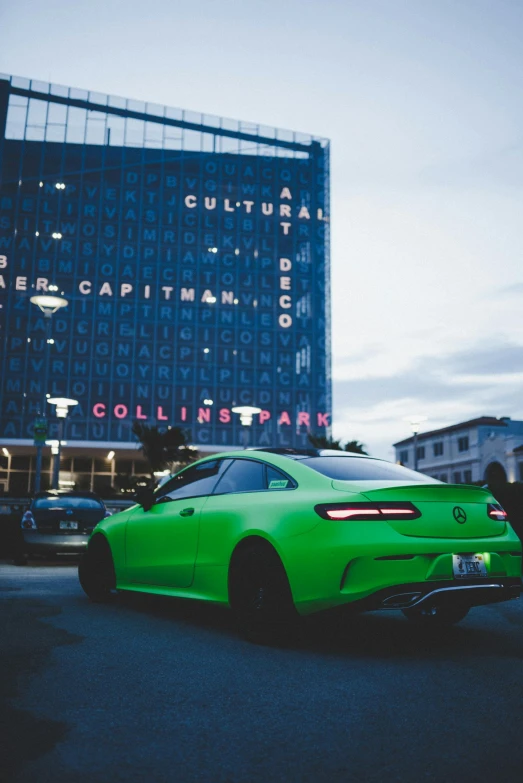 a green sports car parked outside a tall building