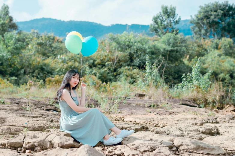 a young lady sits on the ground with two balloons