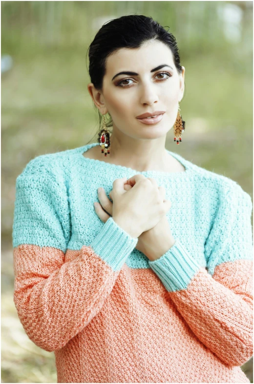 woman with earrings posing in sweater for po