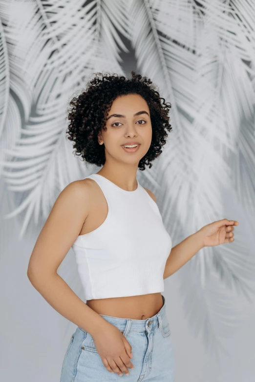 a woman with an afro is wearing jean shorts and a cropped crop top