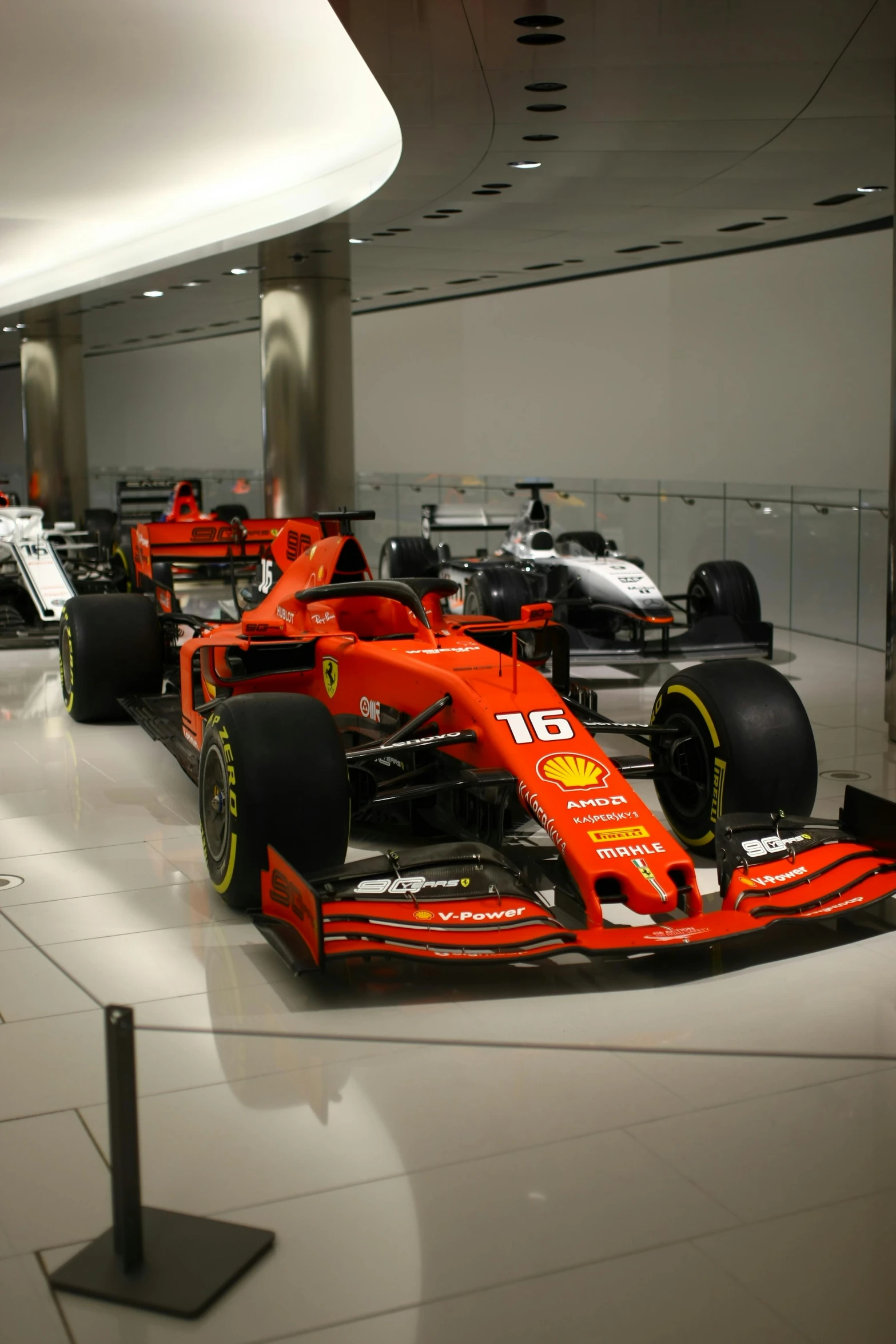 the red race car is behind two other red race cars