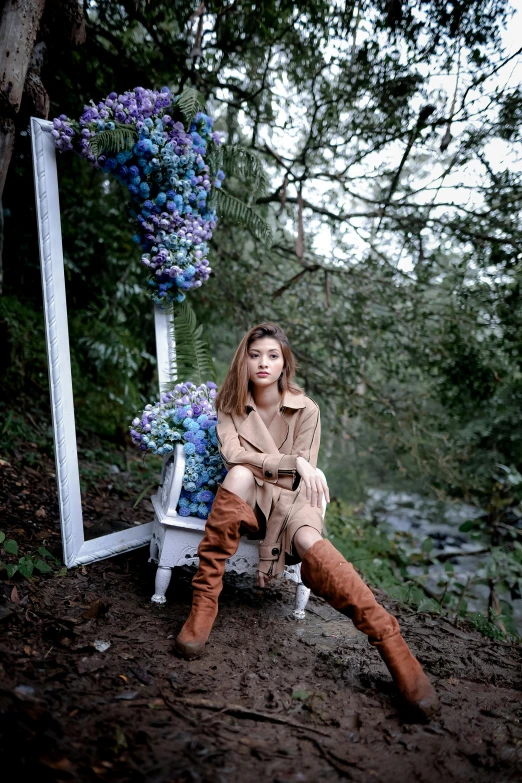 a woman in boots sitting on a bench near flowers