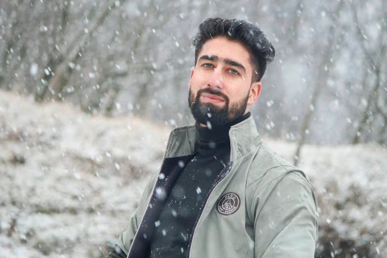 a man in black coat in snowy area with trees