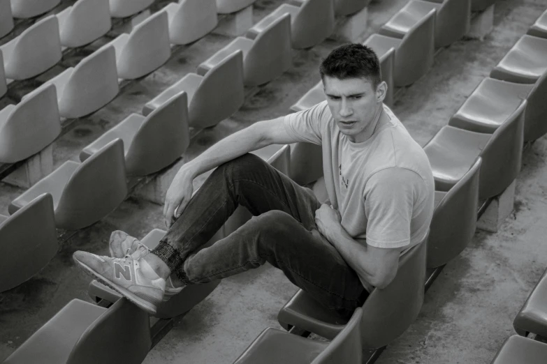 a man with a skateboard sitting in an empty stadium