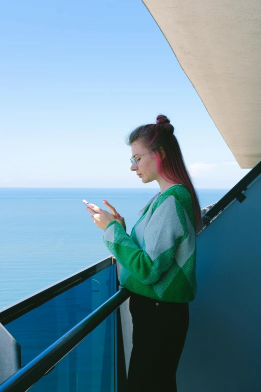 a woman holding a cell phone on top of a balcony