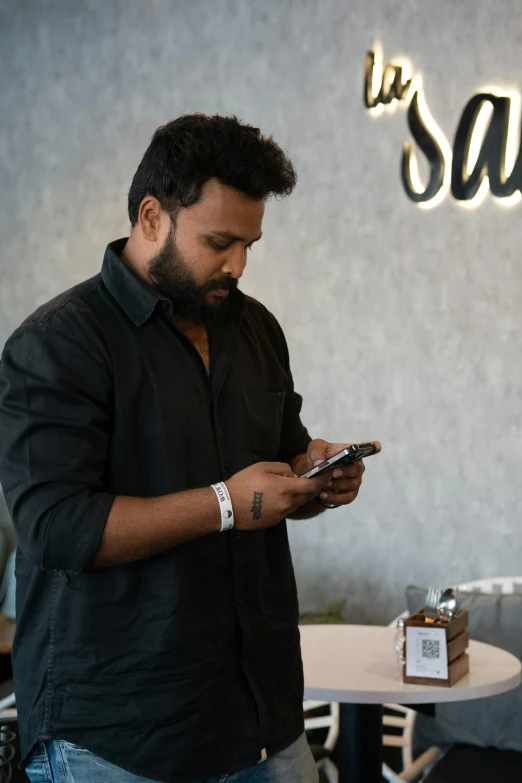 man standing looking at his phone at a restaurant