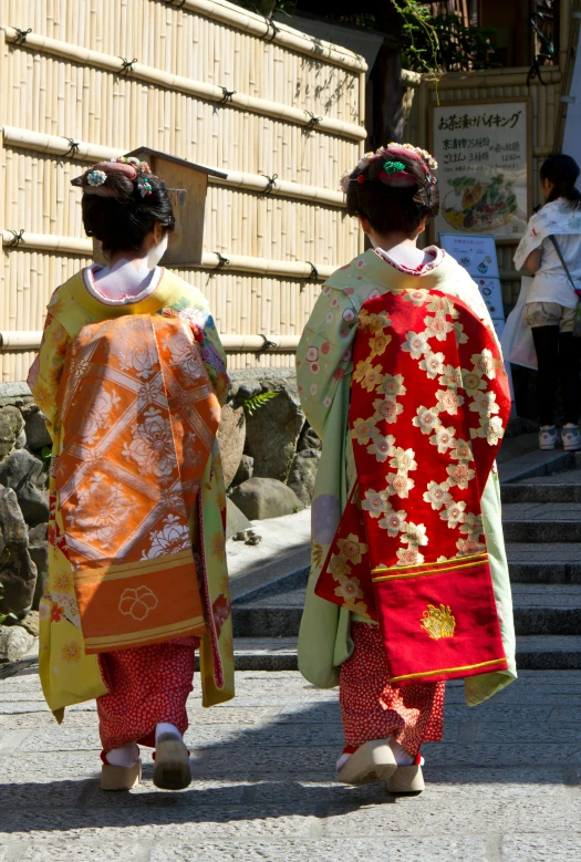 two women dressed in japanese style clothing walk near stone steps