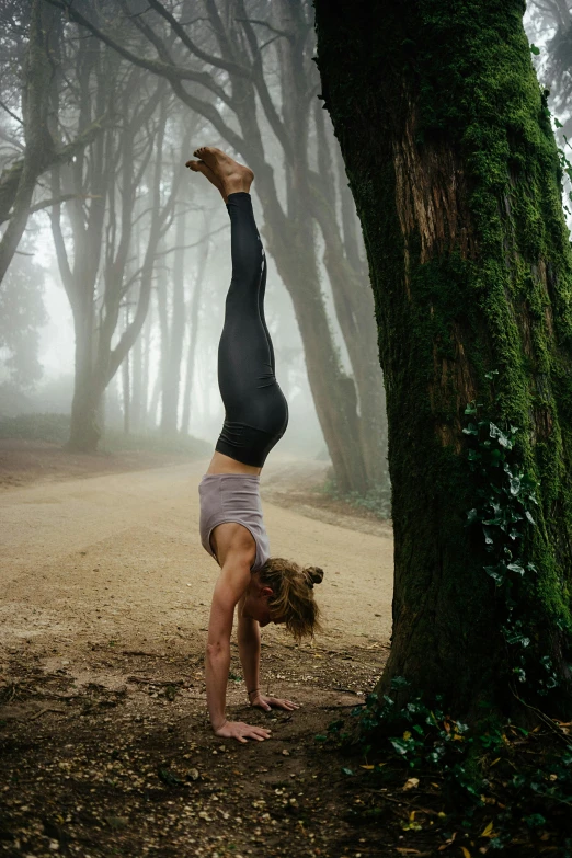 the person is doing yoga exercises under the tree