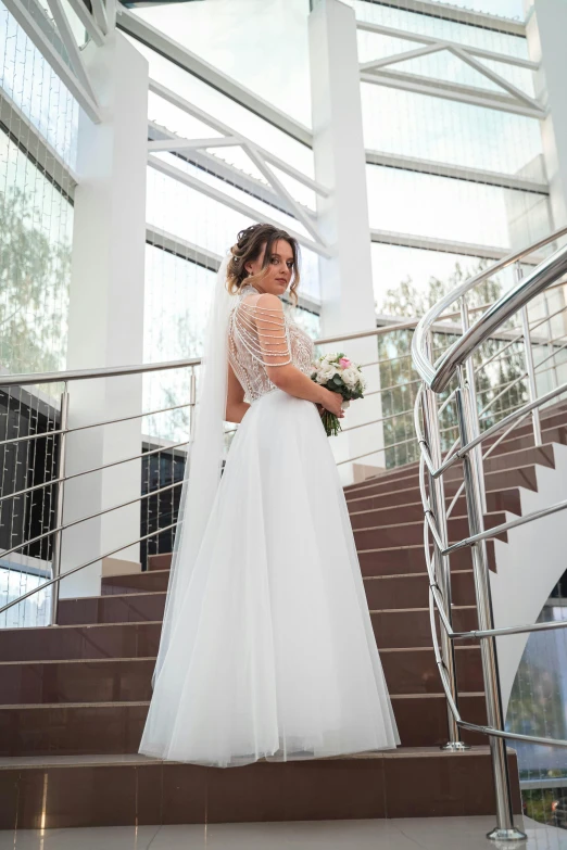 a woman in a wedding dress standing on stairs