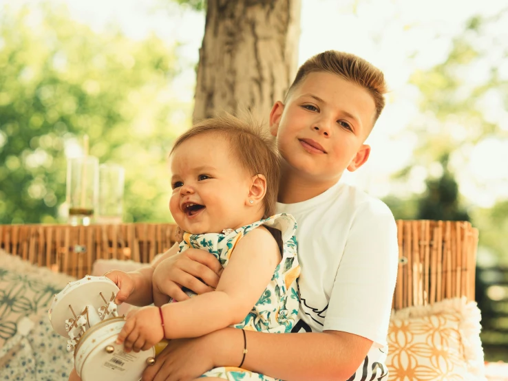 a boy holding a toddler on his chest