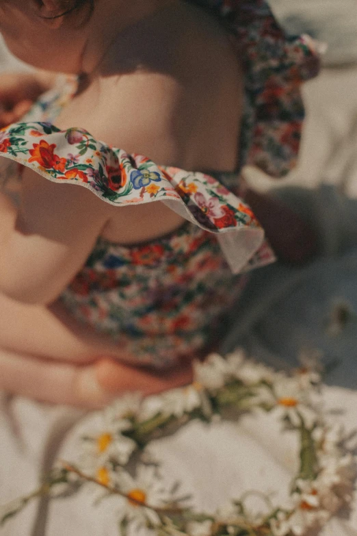 a young baby wearing a dress and headband sitting on a bed