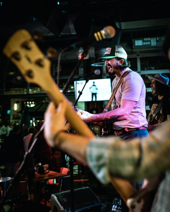 a man plays an electric guitar while other people watch