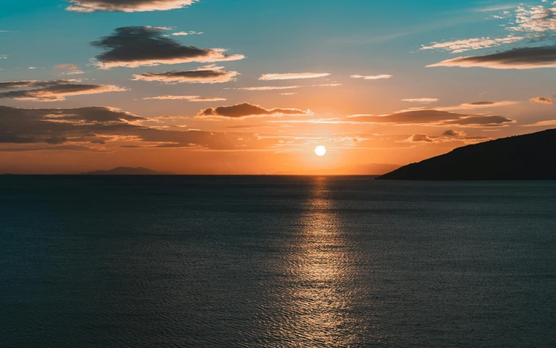 a beautiful sunset over the ocean near a small island