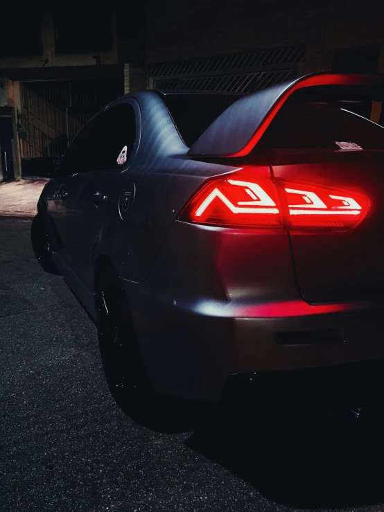 a rear view of a black car at night