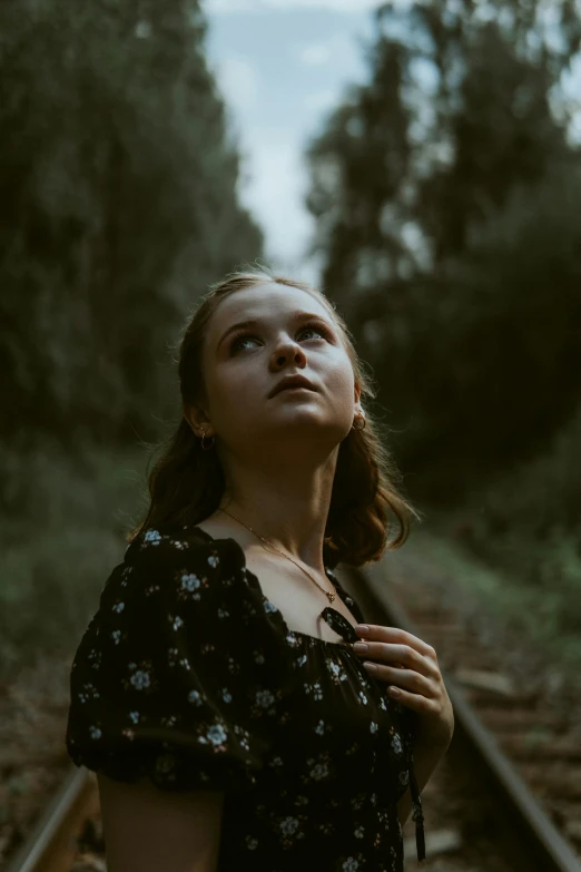 woman in floral dress standing on train tracks