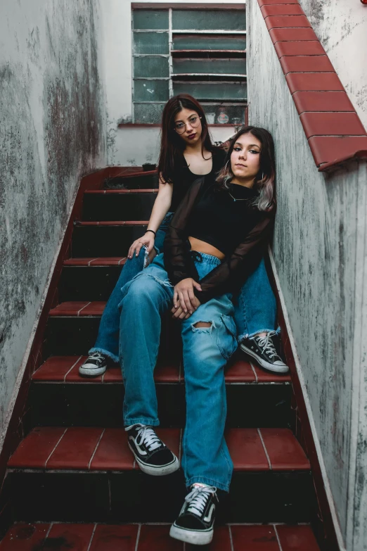 two girls sitting on top of steps in a stairwell