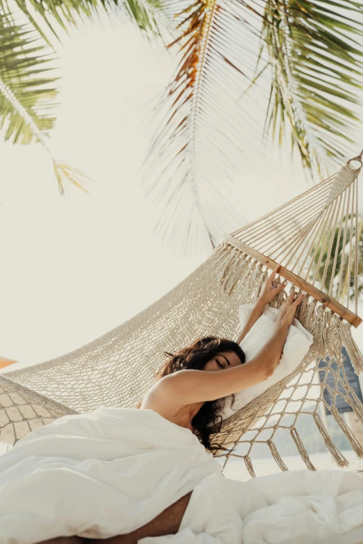 the woman is lying in a hammock on the beach