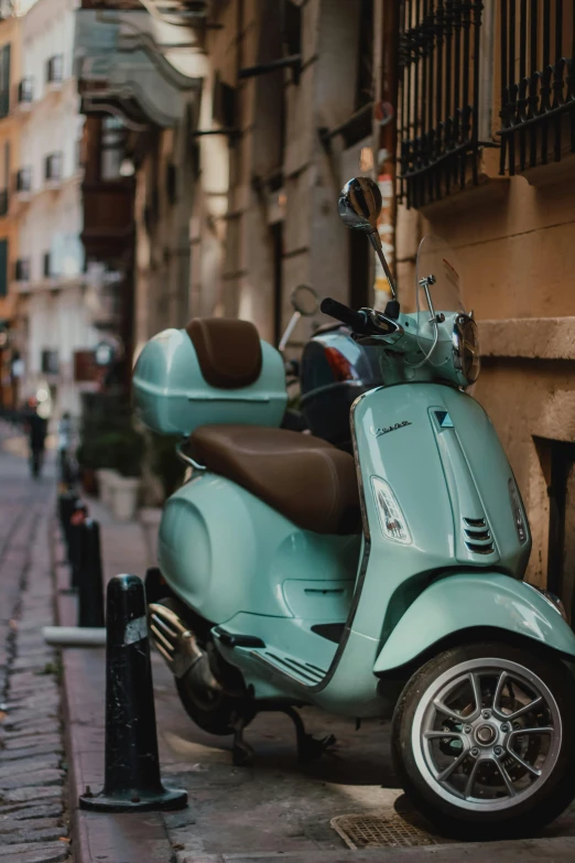 a small, blue moped parked next to a street