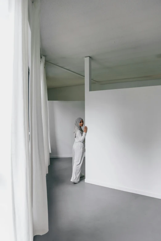 a woman standing in an empty space next to a curtain