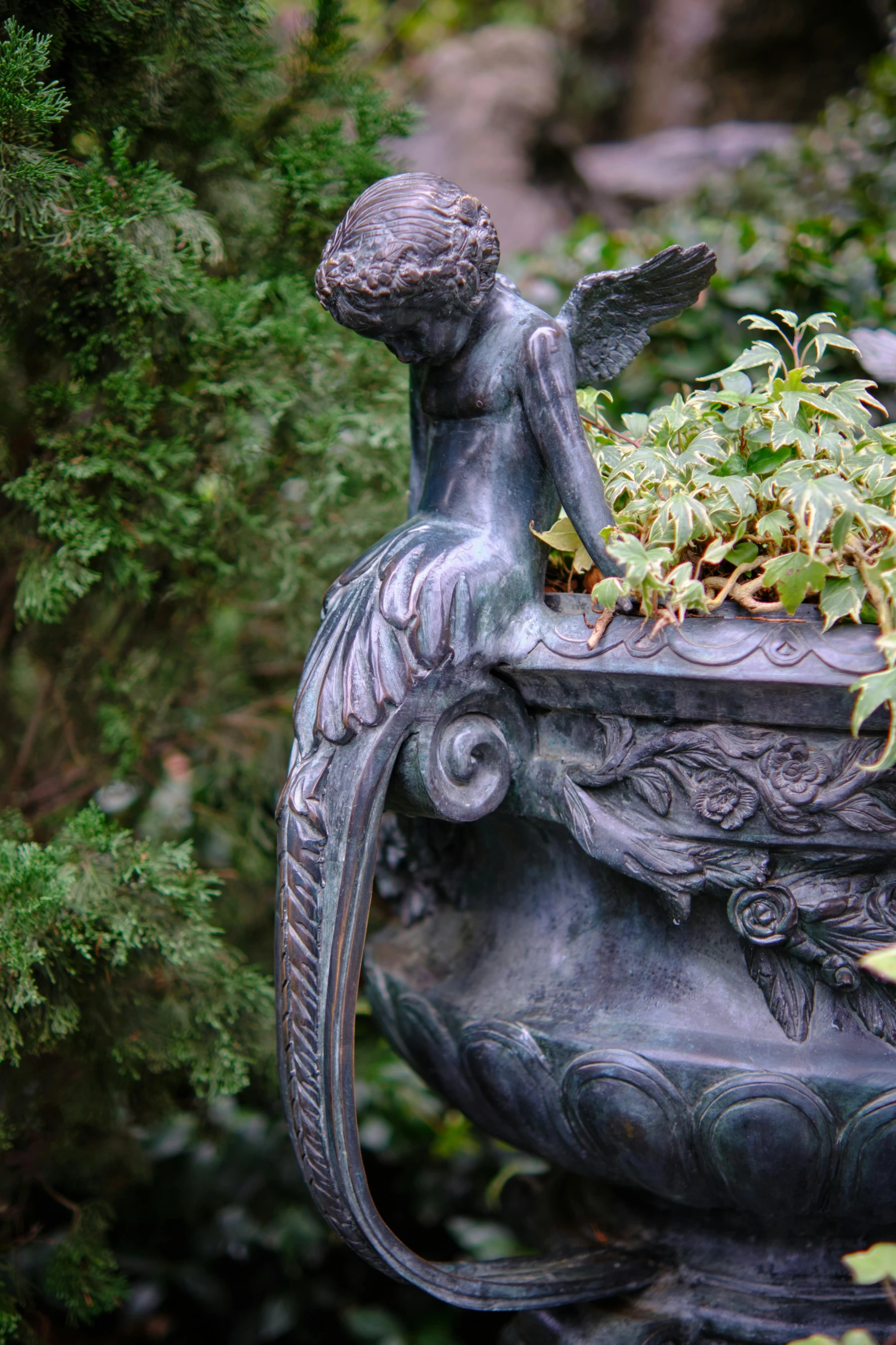 an angel statue holding a pot full of plants