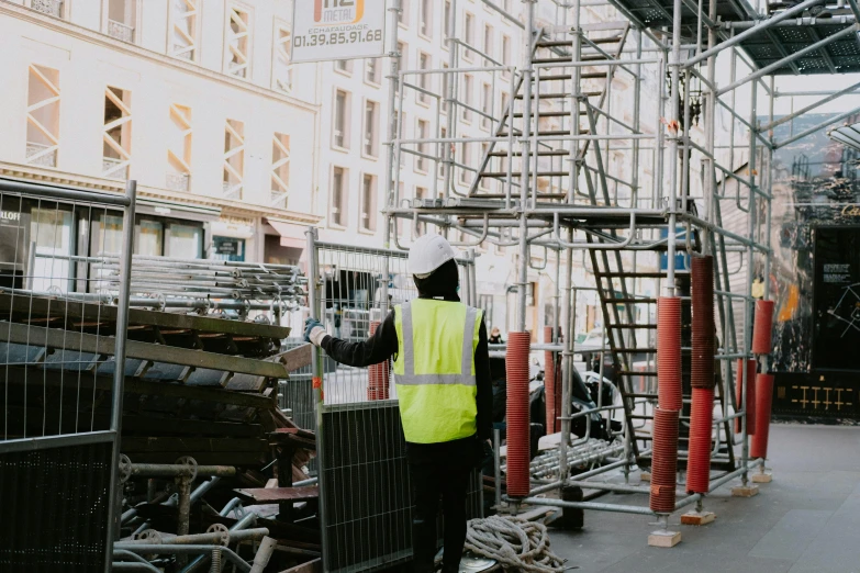 the worker is standing in front of several scaffolding