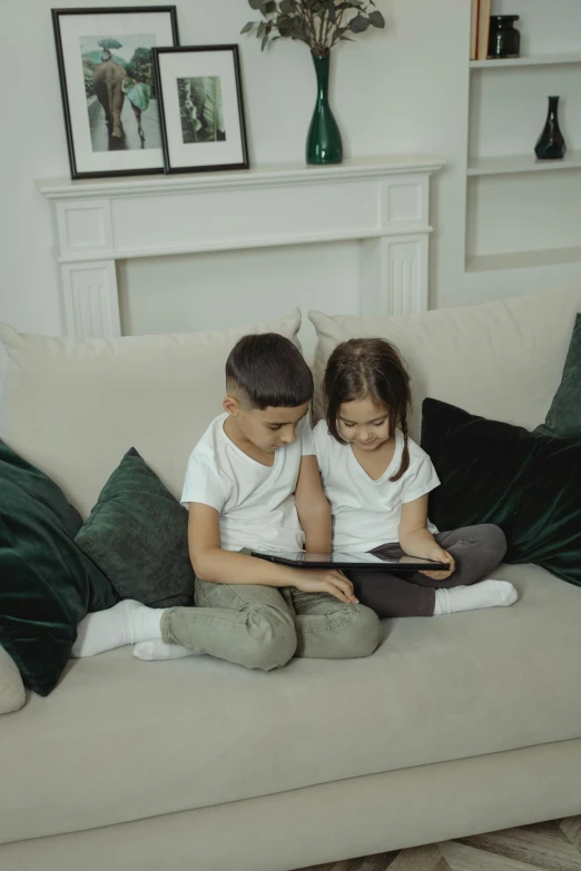 a  and girl sitting on a couch while reading