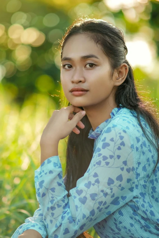 a girl sits in grass, she is wearing a shirt that has hearts on it