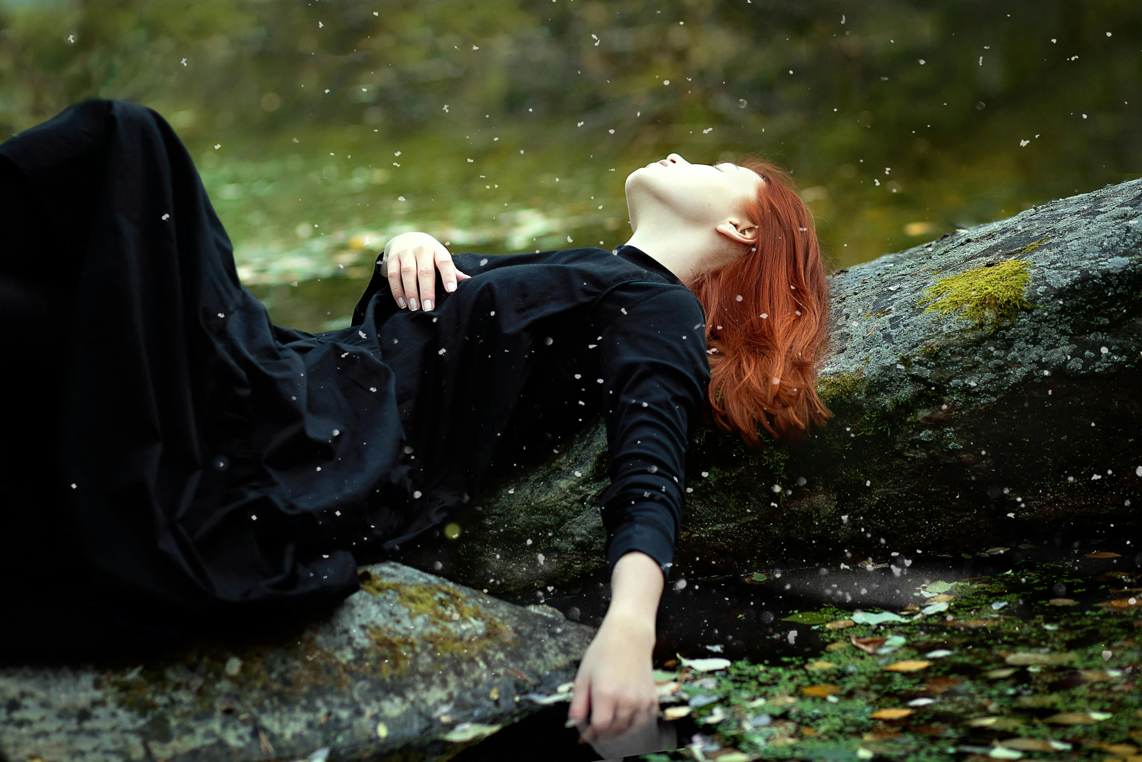 a woman with red hair sitting on a rock in the rain