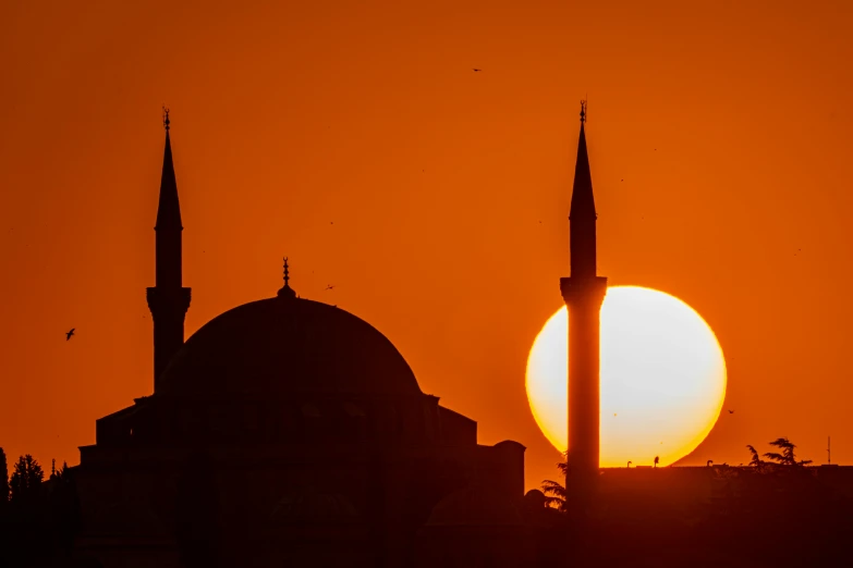 silhouette of the sun setting over a city with buildings