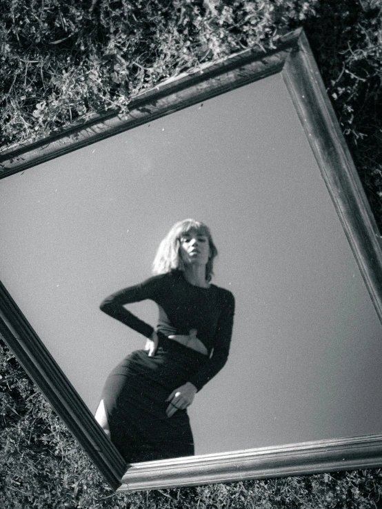 a woman in black clothes stands next to a mirror