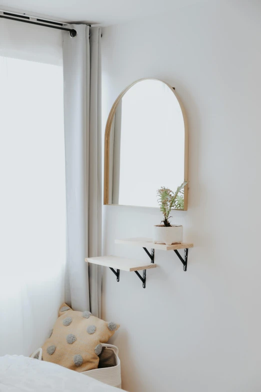 a bedroom scene with a wall mounted mirror and a shelf