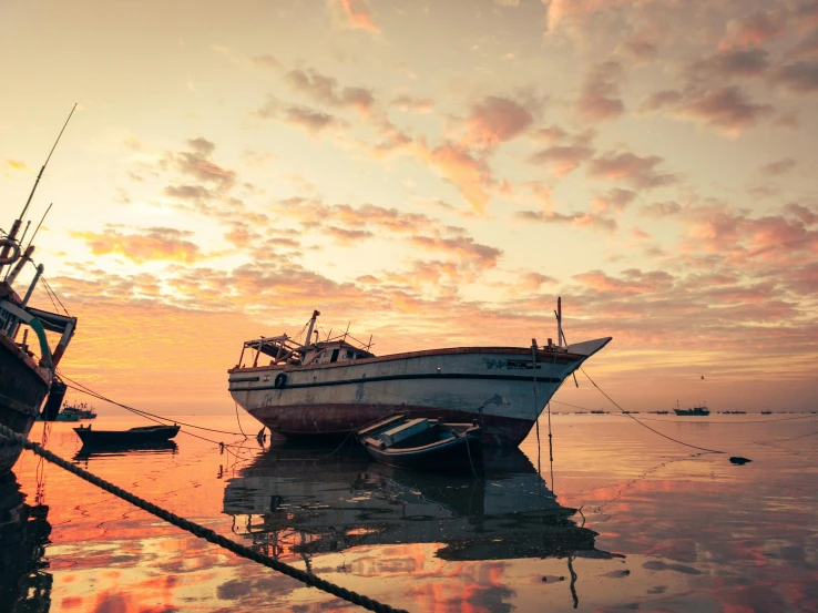 several boats in the ocean during sunset or dawn