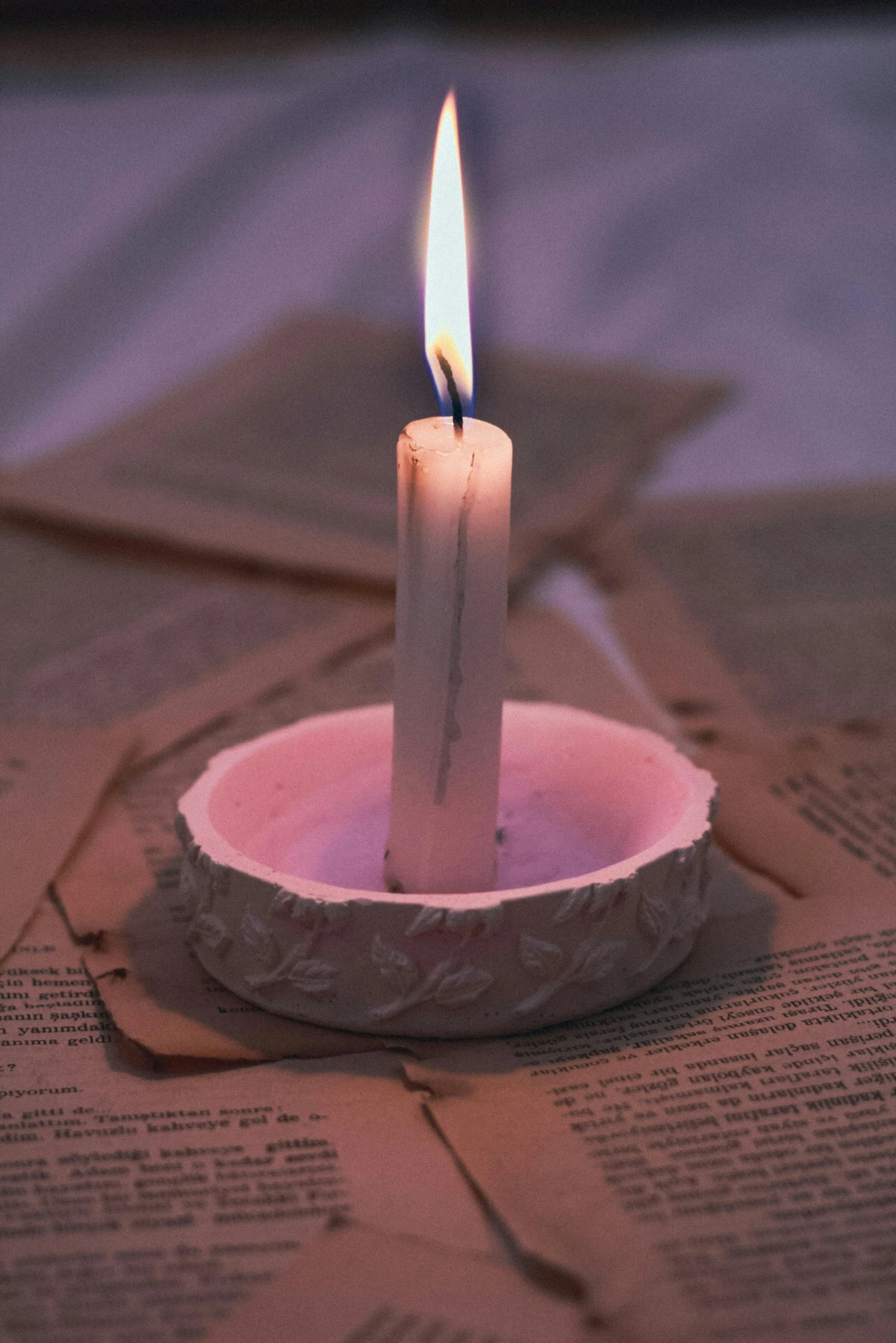 small white candle in a bowl on top of a book