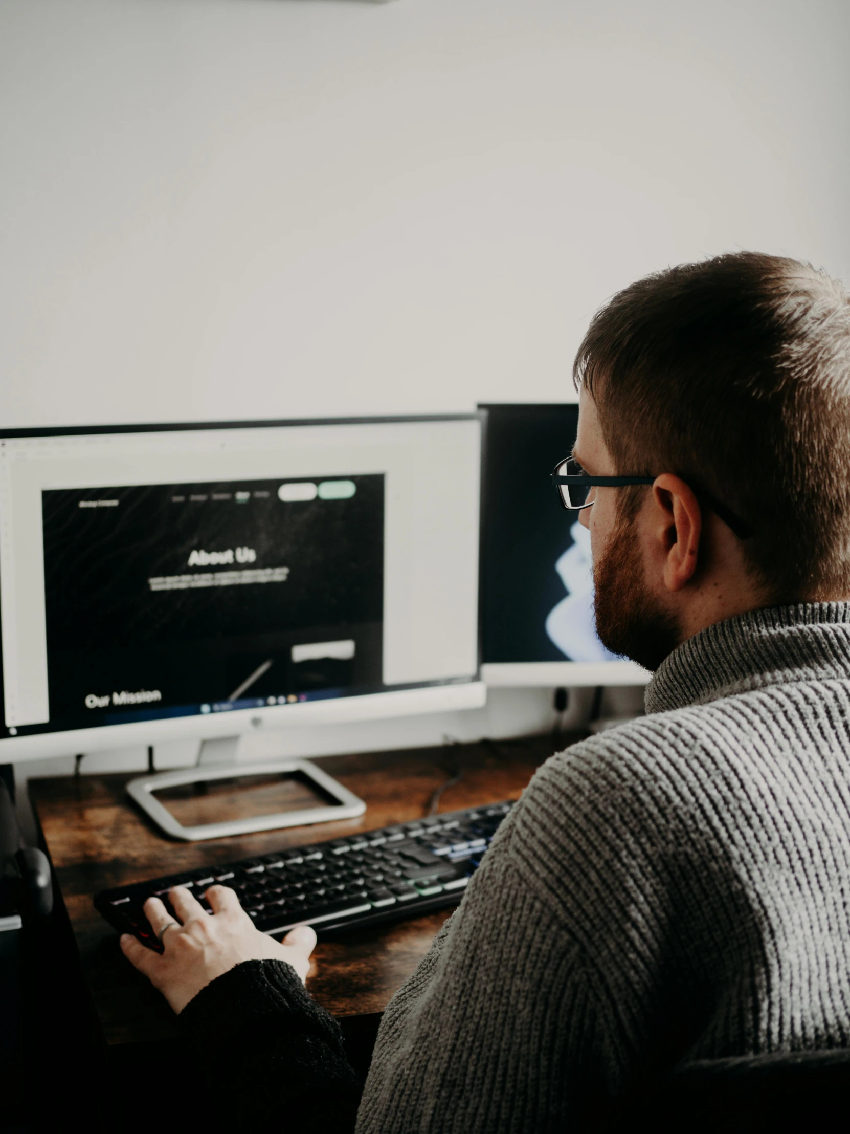 a man with glasses is at a desk using a computer