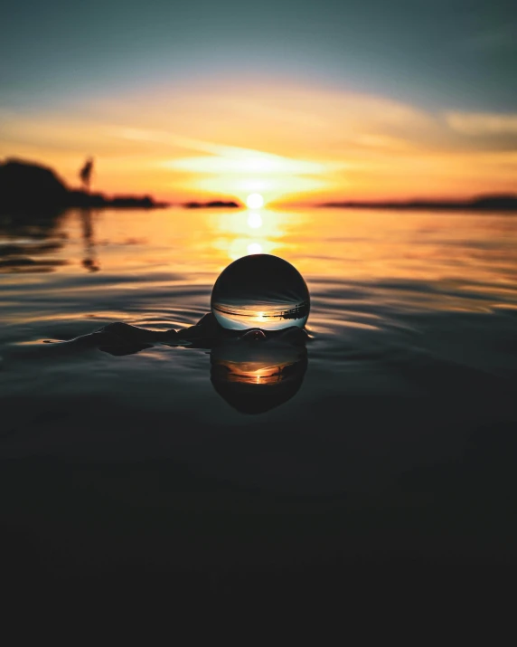 a bubble floats on a body of water during sunset