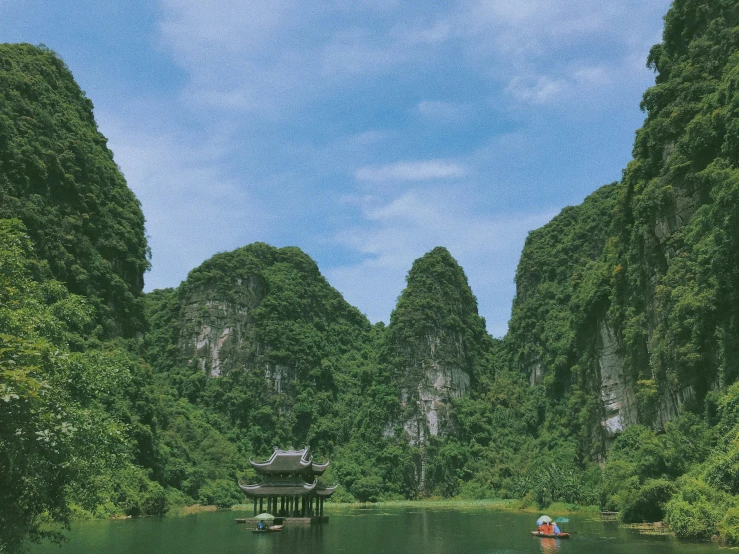 a small boat floating across a lake in the middle of a forest