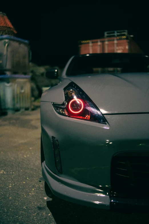 the front end of a silver car with its lights turned on