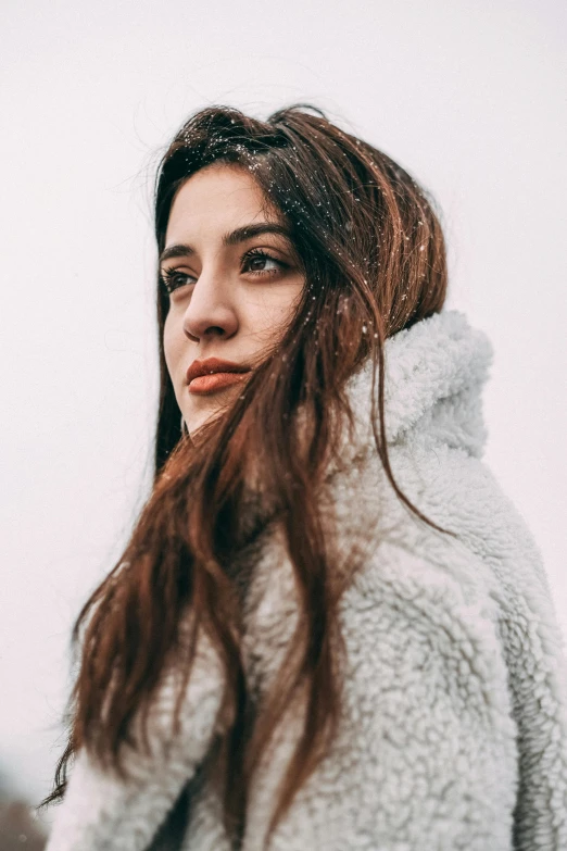 a girl wearing a white jacket is staring ahead