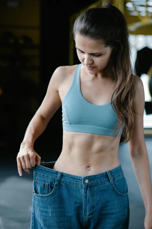 a woman wearing jeans looking at her stomach