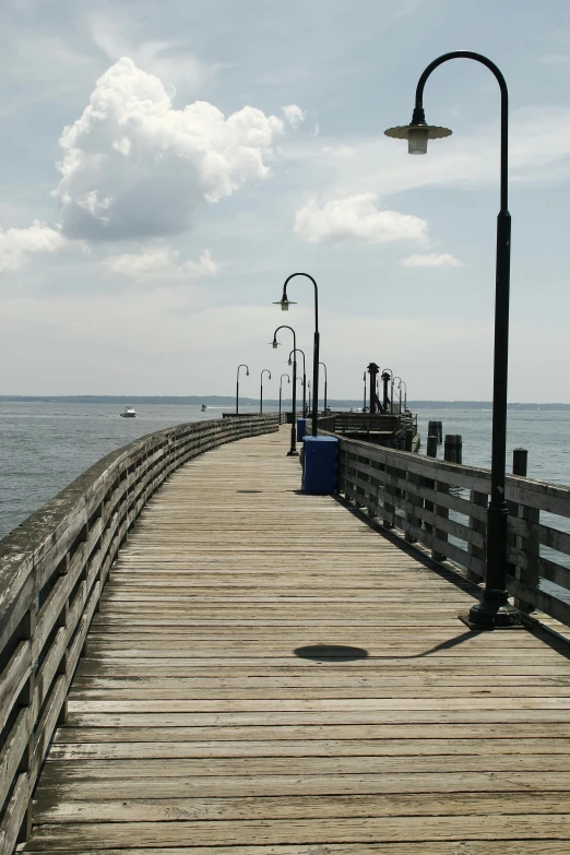 an empty pier in the ocean under a cloudy sky