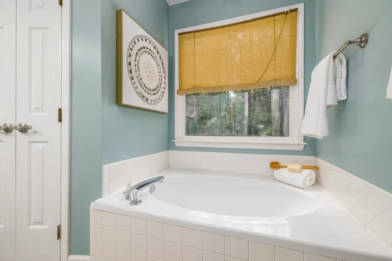 a bathroom with yellow shades on the window and a white tub