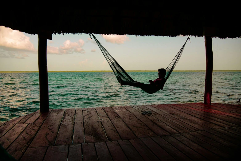 a person is resting in a hammock on the beach