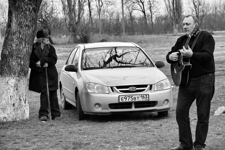 two people are standing outside looking at the broken car